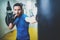 Young muscular kickboxing fighter practicing kicks with punching bag.Boxing on blurred background.Concept of a healthy