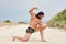 Young muscular man exercising on the beach, young muscular man doing bodibuilding exercises on the beach, athletic young man posin