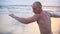 Young muscular man practicing boxing exercises at the sea beach. Male sportsman is practiced self defense alone near