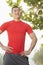 Young muscular man in red shirt standing and smiling, outdoors in a park in Beijing