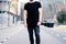 Young muscular man wearing black tshirt and jeans posing on the street of the modern city. Blurred background