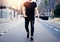 Young muscular man wearing black tshirt and jeans walking on the streets of the modern city. Blurred background