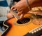 Young musician changing strings on a classical guitar in a guitar shop