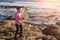 Young musician play the Tuba on rocky sea coast during surf.