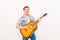 Young musician playing on the guitar and singing on white background