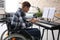 Young musician in wheelchair playing synthesizer at home