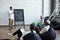 Young Muslim businessman standing by blackboard during speech