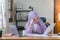 A young Muslim businesswoman wearing a purple hijab is working from home and appears stressed while using her laptop