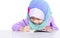 Young muslim girl writing a book on the desk