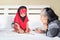 Young muslim girl writing a book with grandma, islamic child do homework at home