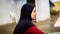 Young Muslim Malay girl with hijab sitting at the stairs at the swimming pool