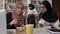 Young muslim women in hijab explaining something to black women in hijab, studying in library and preparing for exams