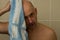 Young naked man wiping his head in towel