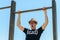 Young nerd tourist man exercising with pull ups against blue sky