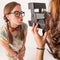 Young nerdy girls using instant camera.