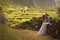 Young newly wedded kissing couple. Attractive woman in white dress hugging man. Romantic background of idyllic landcsape