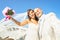 Young newlyweds with bouquet taking selfie against blue sky