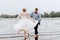 Young newlyweds dance barefoot and have fun on the pier by the water