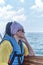 Young nice asian woman in life jacket and sunglasses on pleasure boat on sea.