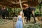 Young nice girl standing near tamed and tied elephants.