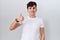 Young non binary man wearing casual white t shirt doing happy thumbs up gesture with hand