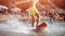 Young novice surfer in yellow shorts learns to catch wave on shore red Board. Background is blurred