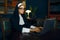 Young nun in a cassock and glasses works on laptop