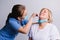 Young nurse in a medical mask takes a COVID 19 test from the nose of an older woman on a white background.