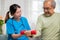 Young nurse physiotherapist support senior old man to lifting dumbell at home