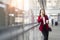 Young office worker girl holding hot espresso paper cup leisurely walking on glass wall