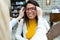 Young ophthalmologist putting on eyeglasses on smiling beautiful woman in optic shop