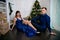 Young ordinary family of two. Young husband and wife near christmas tree. Happy young hetero couple decorate christmas tree at