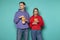 Young outraged couple in casual clothes watching contradictory movie, holding bucket of popcorn