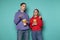 Young outraged couple in casual clothes watching contradictory movie, holding bucket of popcorn