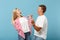 Young overjoyed couple two friends guy girl in white pink empty blank design t-shirts isolated on pastel blue background