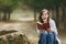 Young overjoyed shocked beautiful woman in casual clothes sitting on stone studying reading book in city park or forest