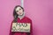 A young overwhelmed girl in red pajamas with a sign `mad christmas ` hanged herself on a Christmas garland from the festive stress