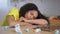 Young overworked exhausted African American woman sleeping at kitchen table with laptop and papers on. Portrait of tired