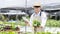 Young owner of a small organic vegetable garden business uses a tablet to control