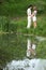 Young pair stands on bank of pond