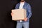 Young parcel delivery man holding a cardboard box in his hands on a black background