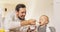 Young parent, father sitting at table holding son next to him, child sitting in feeding