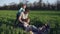 A young parent plays with his grown-up daughters in a meadow, on a litter. He throws the older one over his shoulder