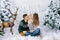 Young parents with a baby sitting in artificial snow in the winter photo zone. Mom and dad kiss the baby