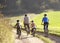 Young parents with children ride bikes in park