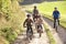 Young parents with children ride bikes in park