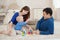 Young parents and cute son play building kit sitting on a carpet in children room