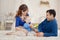 Young parents and cute son play building kit sitting on a carpet in children room