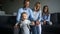 Young parents, husband and wife, and their two daughters are dressed in denim and smiling happily. Happy family at home