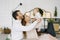 Young parents lift their baby in their arms and smile at him against the background of a bedroom decorated for Christmas and New